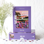 Lila Schachtel des nachhaltigen Puzzles Van Life mit Campervan der durch bunte Landschaft fährt. 