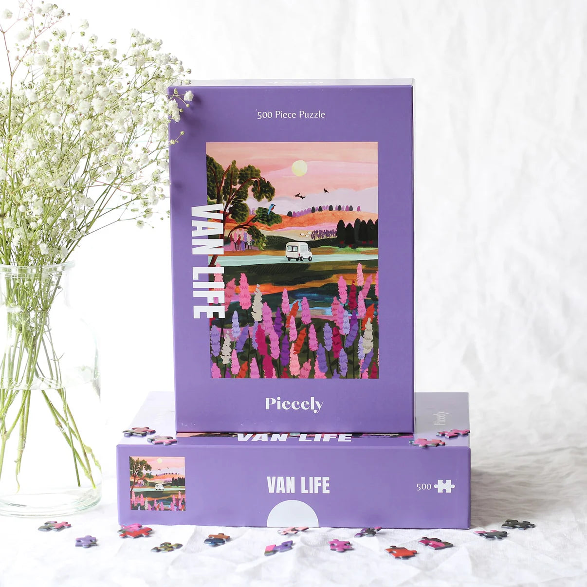 Lila Schachtel des nachhaltigen Puzzles Van Life mit Campervan der durch bunte Landschaft fährt. 