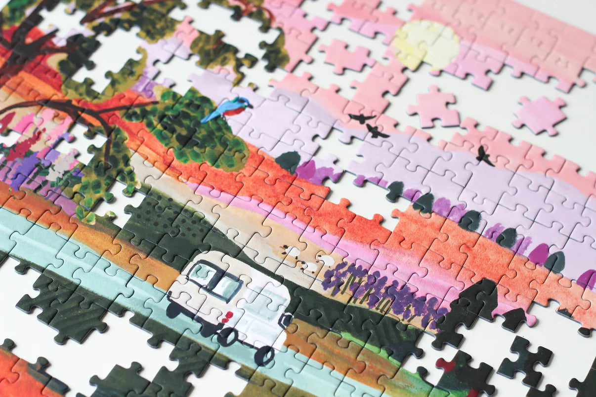 Nahaufnahme eines nachhaltigen Puzzles aus recyceltem Altpapier mit bunter Landschaft und Camper Van. 