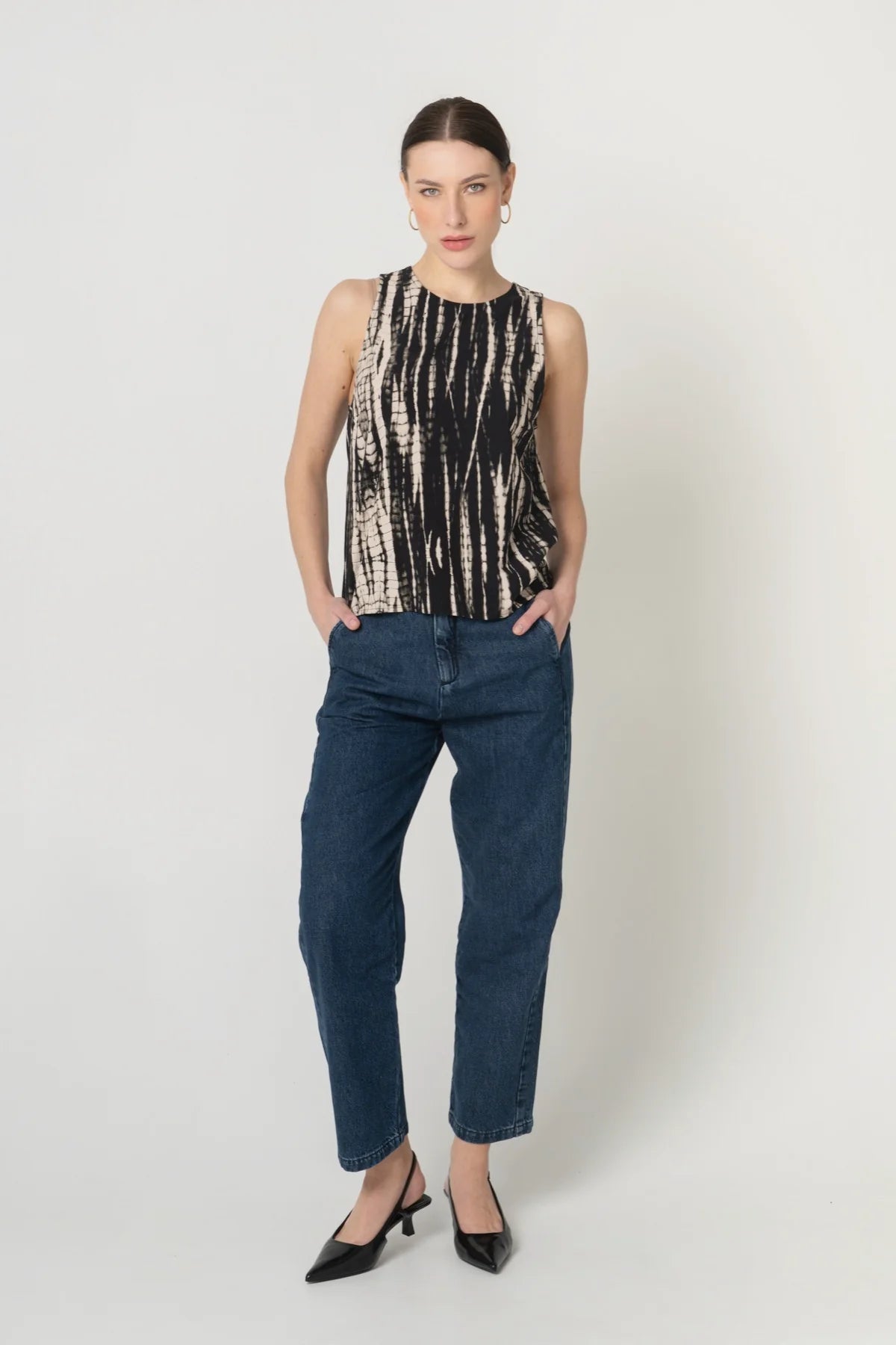 Frau von vorne mit nachhaltigem Top aus Ecovero Viskose in Batik Optik und fair produzierter Jeans in Blau. 