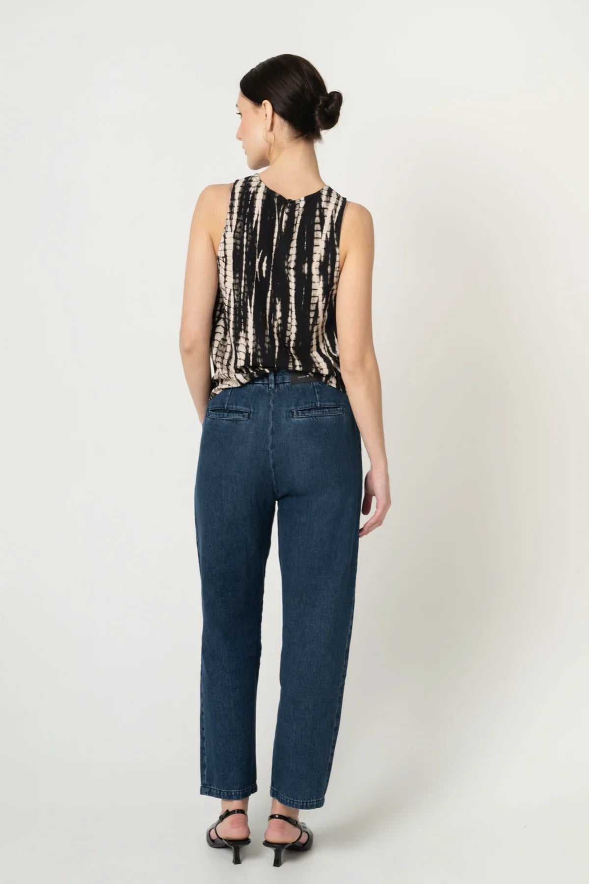 Frau von hinten mit nachhaltigem Top aus Ecovero Viskose in Batik Optik und fair produzierter Jeans in Blau. 